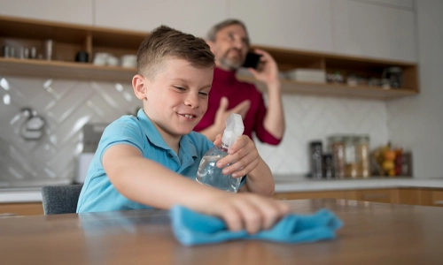 Image of a Smiling Child helping wipe the dining table medium shot