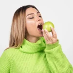 Young woman eating a green apple as part of a healthy lifestyle