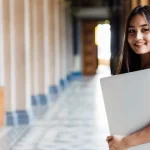 Female university student using a laptop on campus while exploring the best college degree options