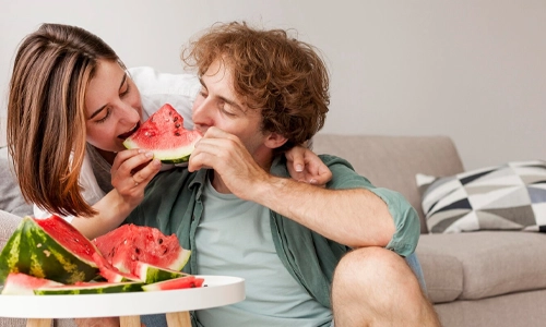Couple eating watermelon together outdoors