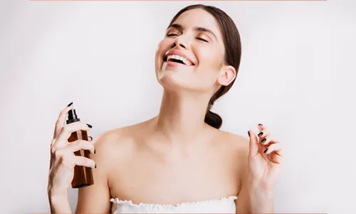 Woman spraying body mist after a shower