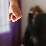 A man folding his hand angrily to beat a woman.