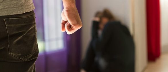 A man folding his hand angrily to beat a woman.