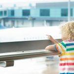 Children conversing by pointing at planes at the airport.