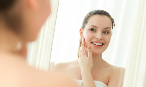 A woman looking at her face in the mirror