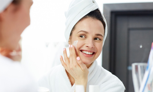 Woman applying moisturizer on her face