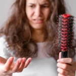 Woman examining hair loss while learning natural remedies for hair regrowth
