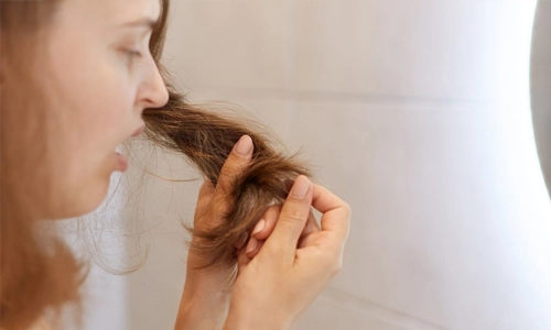 Closeup image of an upset, astonished woman looking at her dry hair.