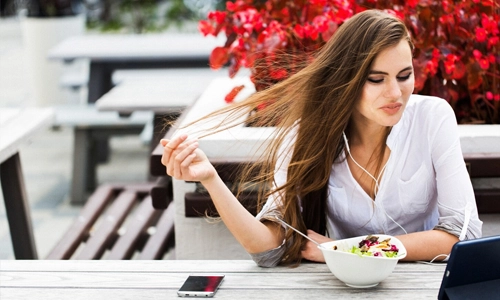 Image of a woman watches something on her tablet while sitting in the restaurant