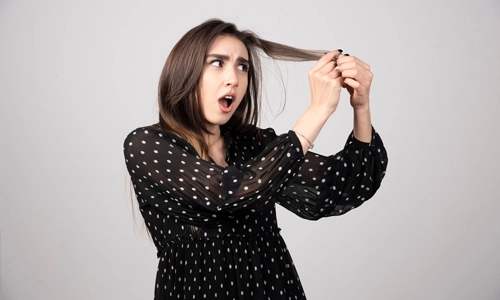 A beautiful young woman holding her healthy and shiny hair.