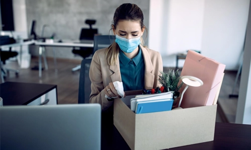 Sad businesswoman packing her belongings while getting fired from work due to covid19 pandemic