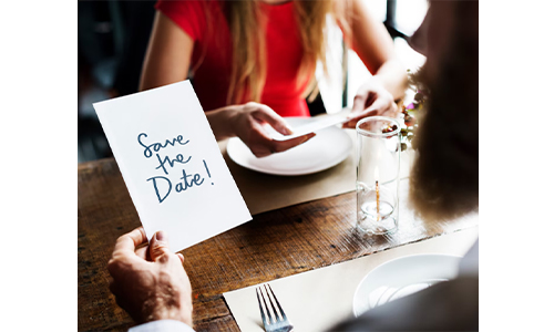 Man holding a party invitation card that says 'Save the Date'