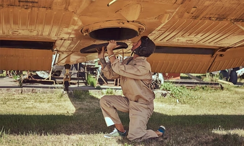 Aircraft mechanic inspecting the underside of a plane during maintenance