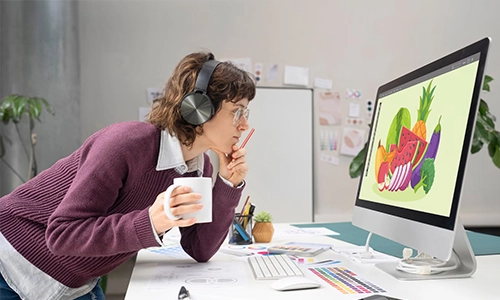 Woman working on a colorful digital illustration at a computer in a creative studio