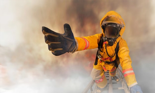 Firefighter in protective gear reaching forward through smoke during an emergency response