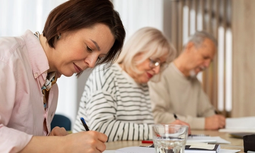 Medium shot people writing in a notebook on a desk