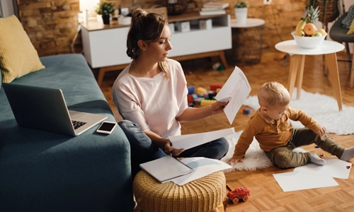 Stay at home mother working while being in the living room with her son