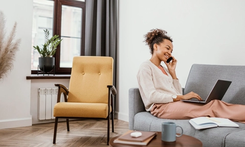 Woman working while sitting on the sofa and talking over phone