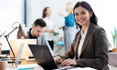 Medium shot woman working on laptop in an office background.