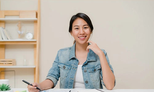 Woman writing in a notebook while sitting at a desk in a home office